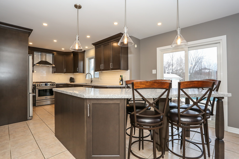 Example of a mid-sized transitional u-shaped enclosed kitchen design in Toronto with an undermount sink, recessed-panel cabinets, dark wood cabinets, quartz countertops, white backsplash, porcelain backsplash, stainless steel appliances and an island