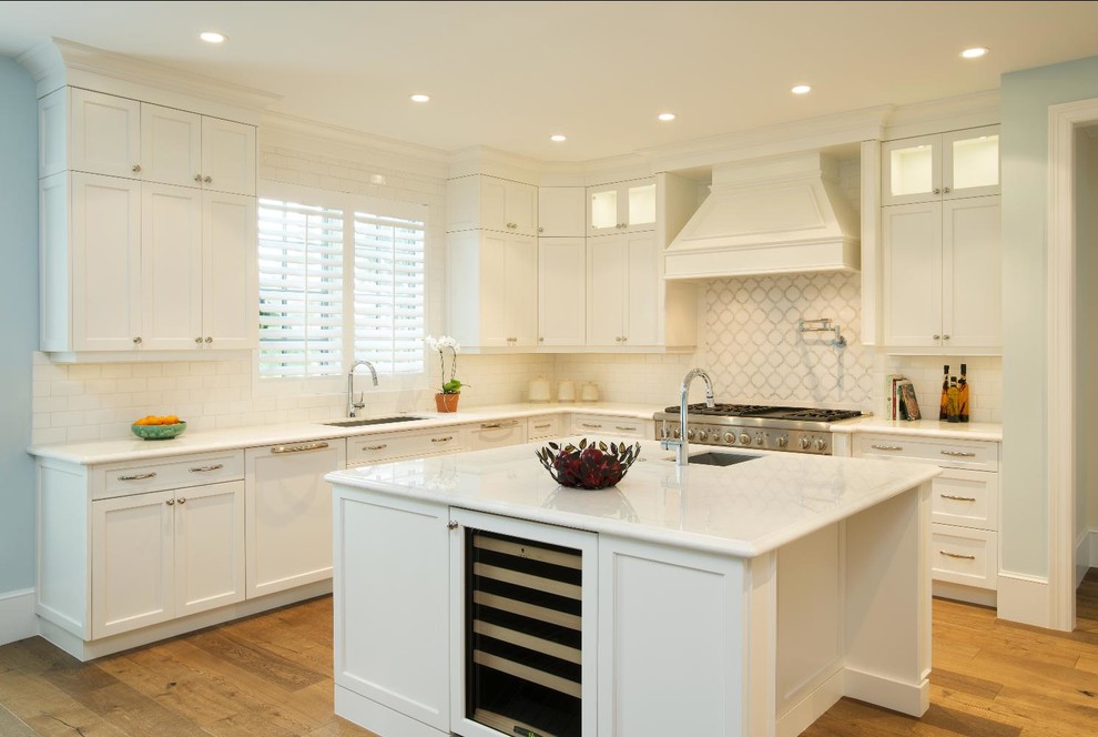 Mid-sized elegant light wood floor eat-in kitchen photo with flat-panel cabinets, an island, white cabinets, white backsplash, subway tile backsplash, stainless steel appliances and blue walls