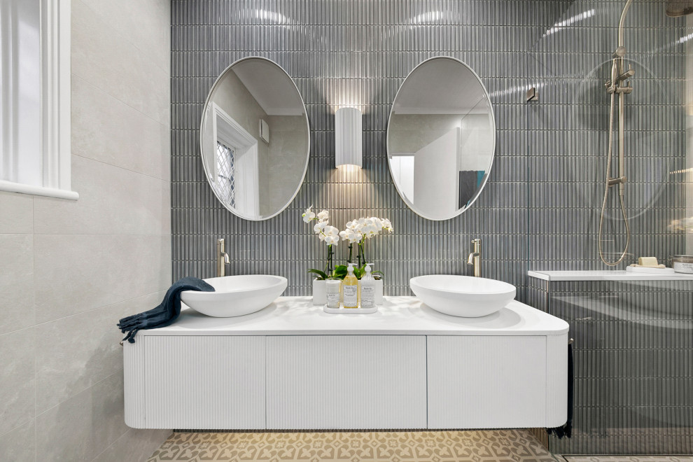 Пример оригинального дизайна: ванная комната среднего размера с фасадами с декоративным кантом, белыми фасадами, душем в нише, унитазом-моноблоком, разноцветной плиткой, керамической плиткой, разноцветными стенами, полом из керамической плитки, душевой кабиной, настольной раковиной, столешницей из искусственного камня, серым полом, открытым душем, белой столешницей, тумбой под две раковины, подвесной тумбой и потолком из вагонки