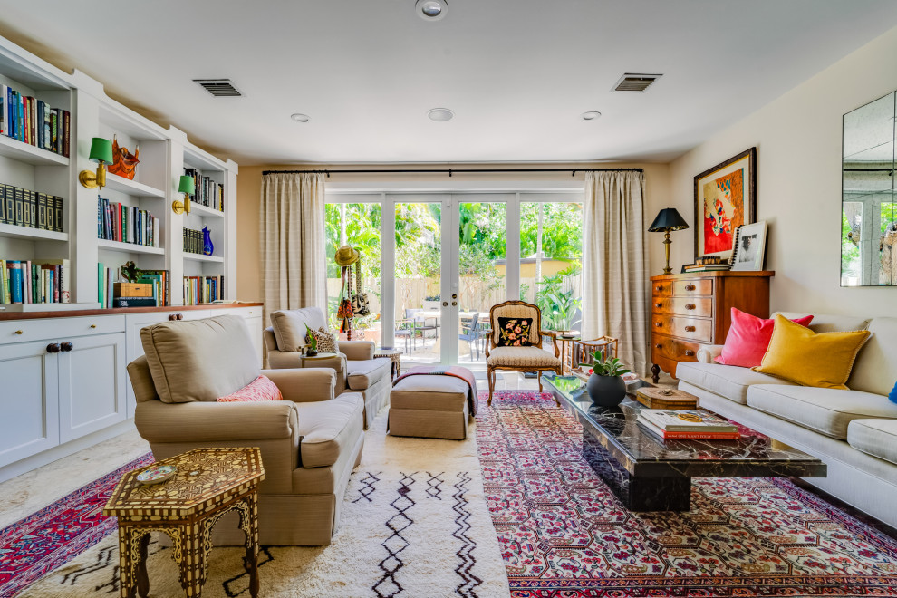 Photo of a large eclectic open concept living room in Miami with a library, travertine floors, no fireplace, no tv, beige floor and beige walls.