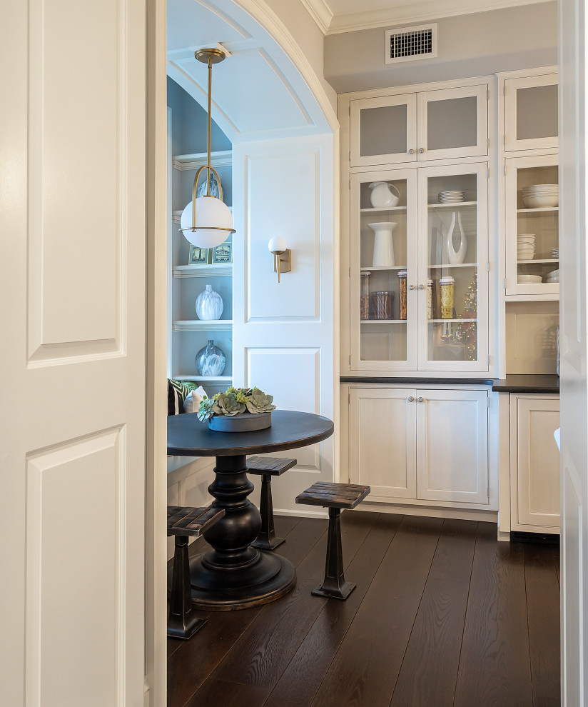 Example of a transitional galley dark wood floor and brown floor kitchen design in Other with a farmhouse sink, shaker cabinets, white cabinets, white backsplash, porcelain backsplash, stainless steel appliances, a peninsula, black countertops and soapstone countertops