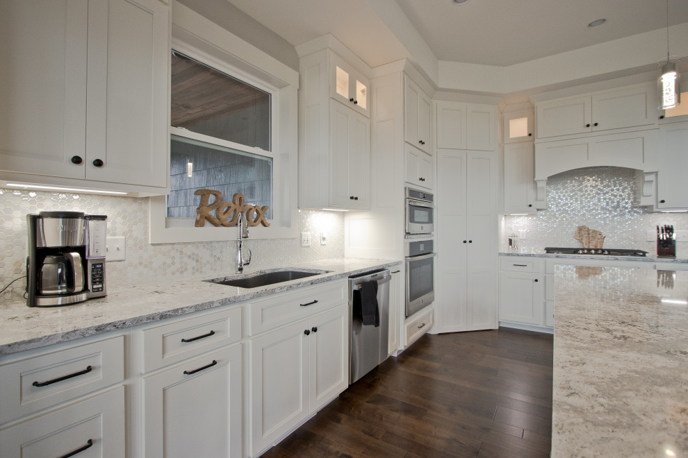 This is an example of a transitional l-shaped eat-in kitchen in Other with an undermount sink, shaker cabinets, white cabinets, quartz benchtops, white splashback, mosaic tile splashback, stainless steel appliances, medium hardwood floors, with island, brown floor, white benchtop and coffered.