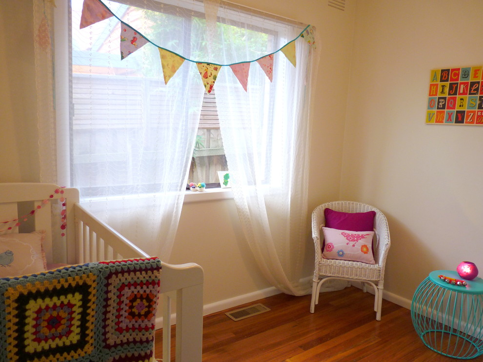 Imagen de habitación de bebé niña clásica de tamaño medio con paredes blancas, suelo de madera oscura y suelo marrón