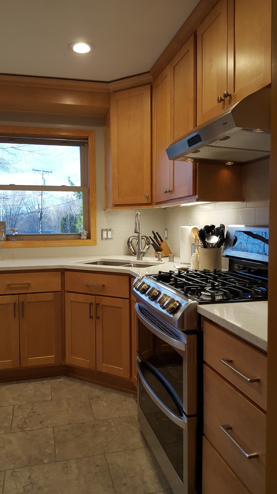 Eat-in kitchen - mid-sized transitional l-shaped ceramic tile eat-in kitchen idea with an undermount sink, shaker cabinets, light wood cabinets, quartz countertops, gray backsplash, subway tile backsplash, stainless steel appliances and no island