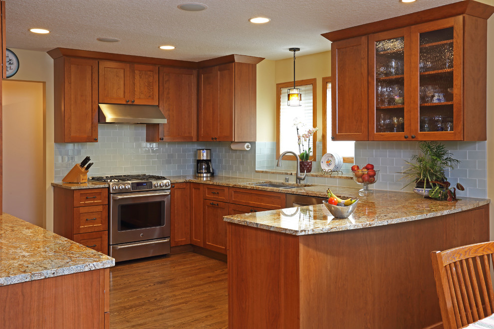 Example of a mid-sized transitional u-shaped medium tone wood floor eat-in kitchen design in Minneapolis with an undermount sink, shaker cabinets, medium tone wood cabinets, granite countertops, cement tile backsplash, stainless steel appliances, a peninsula and multicolored countertops
