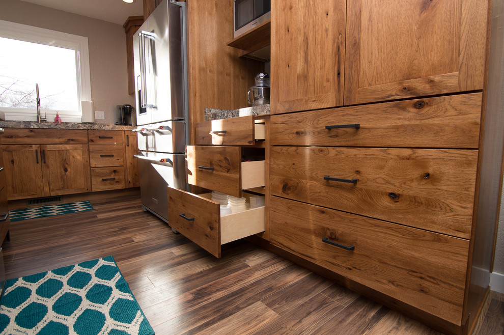 Example of a mid-sized transitional l-shaped medium tone wood floor and brown floor eat-in kitchen design with an integrated sink, shaker cabinets, medium tone wood cabinets, laminate countertops, stainless steel appliances, an island and beige countertops