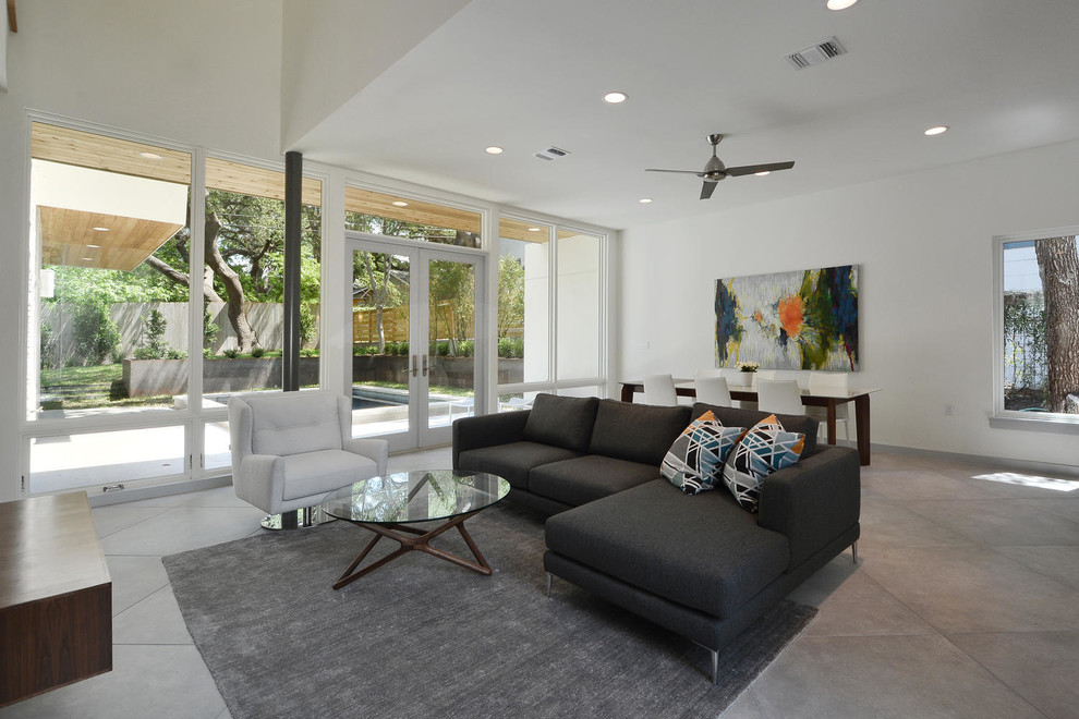 This is an example of a modern formal open concept living room in Austin with white walls, porcelain floors and a concealed tv.