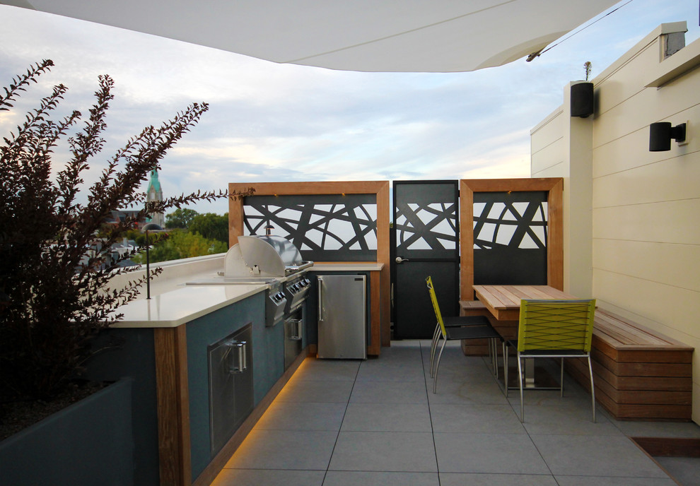 Photo of a small modern rooftop deck in Chicago with an outdoor kitchen and an awning.