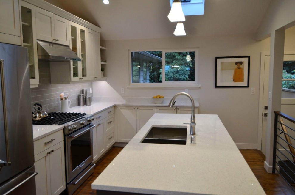 Small transitional u-shaped medium tone wood floor and brown floor kitchen photo in Seattle with an undermount sink, recessed-panel cabinets, white cabinets, quartz countertops, gray backsplash, glass tile backsplash, stainless steel appliances, an island and white countertops