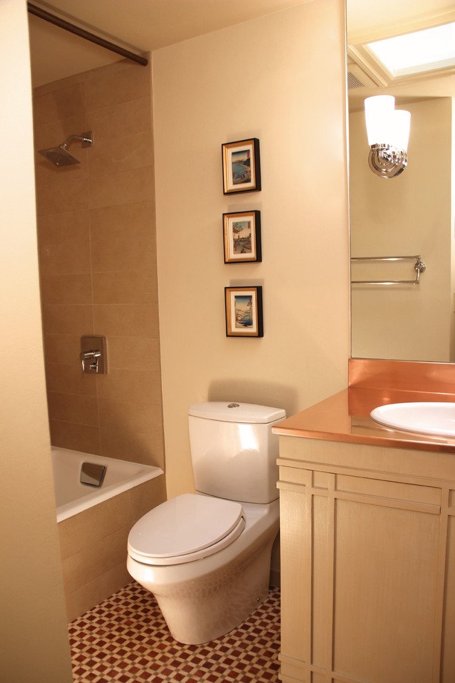 This is an example of a small eclectic bathroom in Seattle with a drop-in sink, furniture-like cabinets, beige cabinets, copper benchtops, a drop-in tub, a shower/bathtub combo, a two-piece toilet, multi-coloured tile, mosaic tile, beige walls and marble floors.
