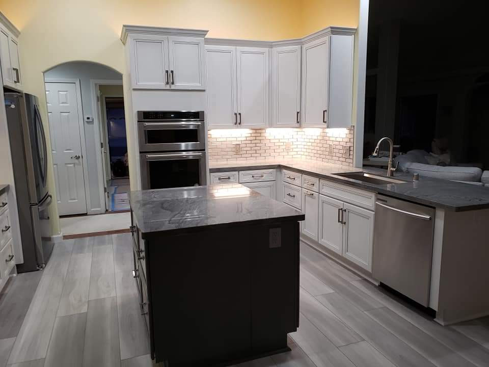 Gray floor kitchen photo with an undermount sink, quartzite countertops, glass tile backsplash, stainless steel appliances, an island and gray countertops