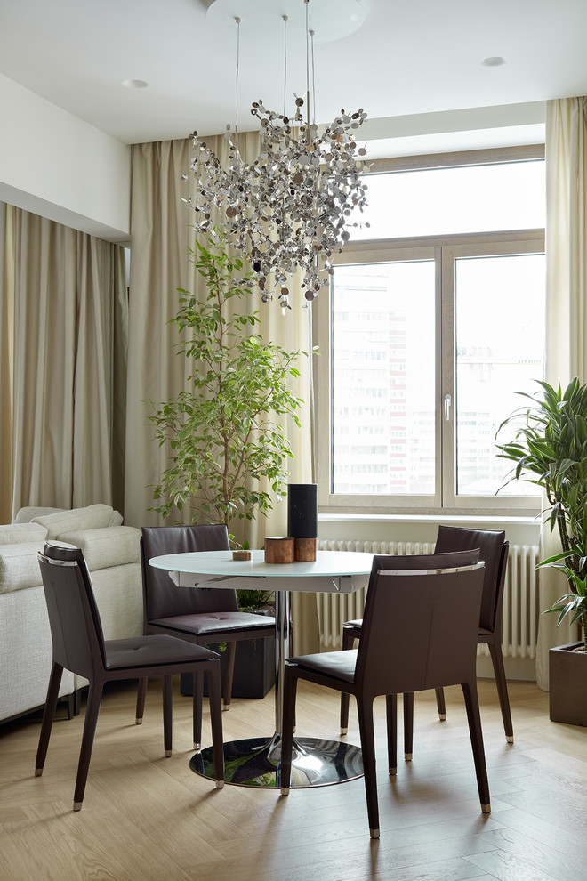 Inspiration pour une salle à manger ouverte sur le salon design avec un mur blanc, parquet clair et un sol beige.