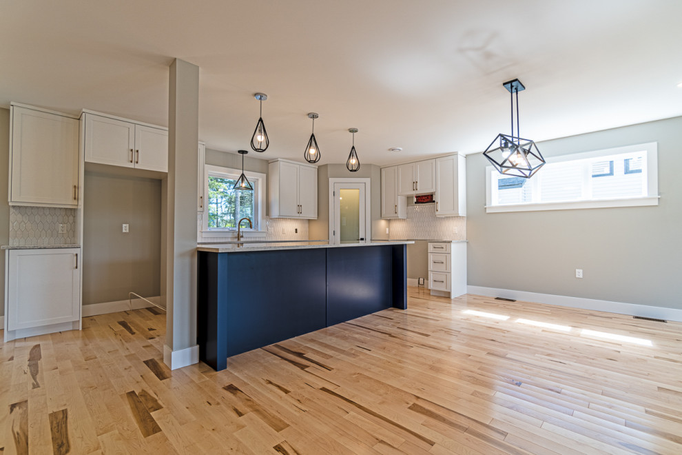 Eat-in kitchen - mid-sized transitional light wood floor and beige floor eat-in kitchen idea with an undermount sink, shaker cabinets, white cabinets, granite countertops, white backsplash, ceramic backsplash, an island and gray countertops