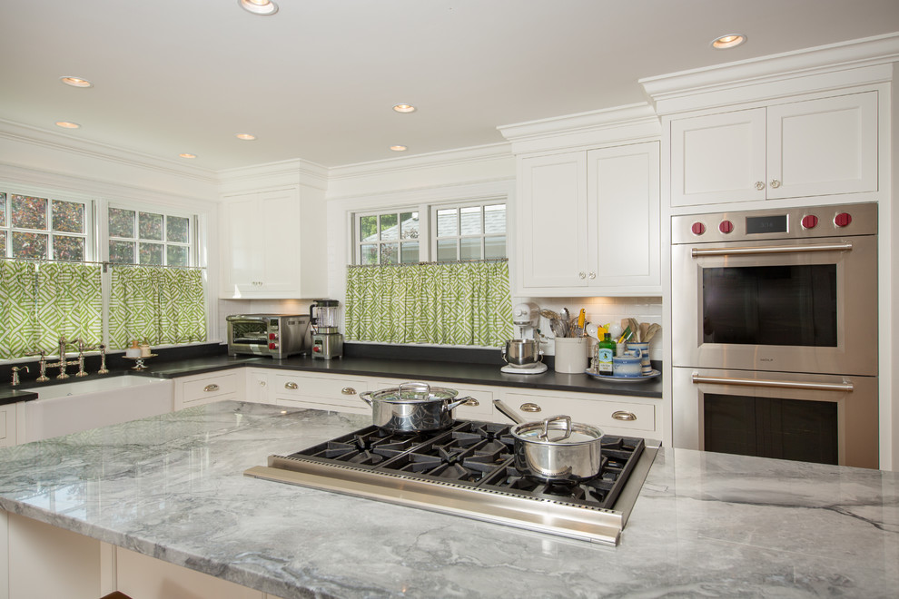 Kitchen - transitional medium tone wood floor kitchen idea in Boston with a farmhouse sink, recessed-panel cabinets, white cabinets, granite countertops, white backsplash, subway tile backsplash, stainless steel appliances and two islands