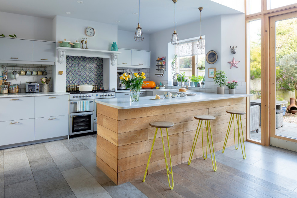 Design ideas for a mid-sized eclectic u-shaped kitchen in Sussex with a farmhouse sink, flat-panel cabinets, quartzite benchtops, grey splashback, ceramic splashback, white appliances, concrete floors, with island, brown floor, blue benchtop and coffered.