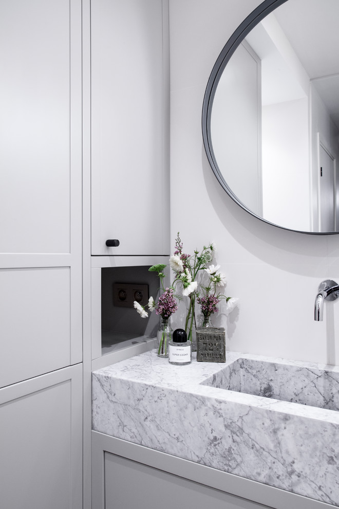 This is an example of a mid-sized contemporary master bathroom in Paris with shaker cabinets, grey cabinets, a curbless shower, white tile, ceramic tile, white walls, marble floors, an integrated sink, marble benchtops, white floor, a hinged shower door, white benchtops, a shower seat, a double vanity and a floating vanity.