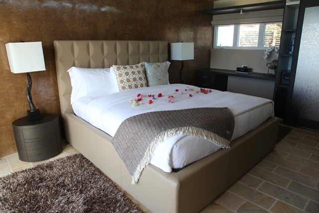 Large beach style loft-style bedroom with travertine floors.