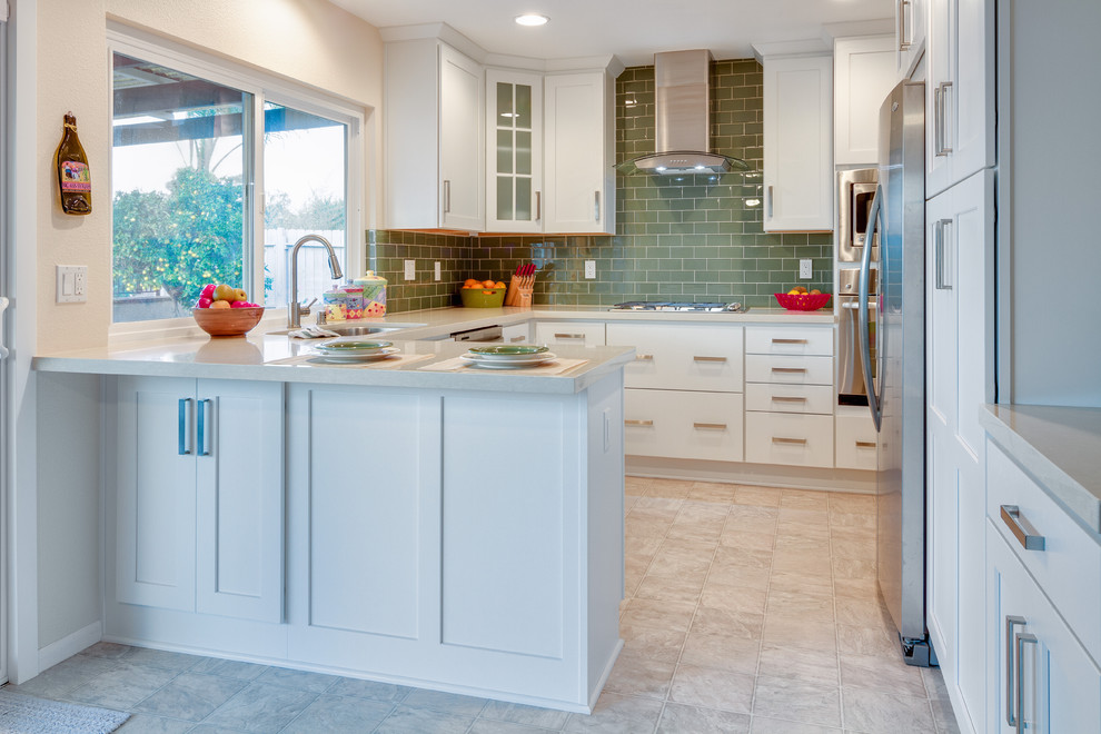 This is an example of a traditional u-shaped eat-in kitchen in San Diego with a drop-in sink, glass-front cabinets, white cabinets, green splashback, subway tile splashback and stainless steel appliances.