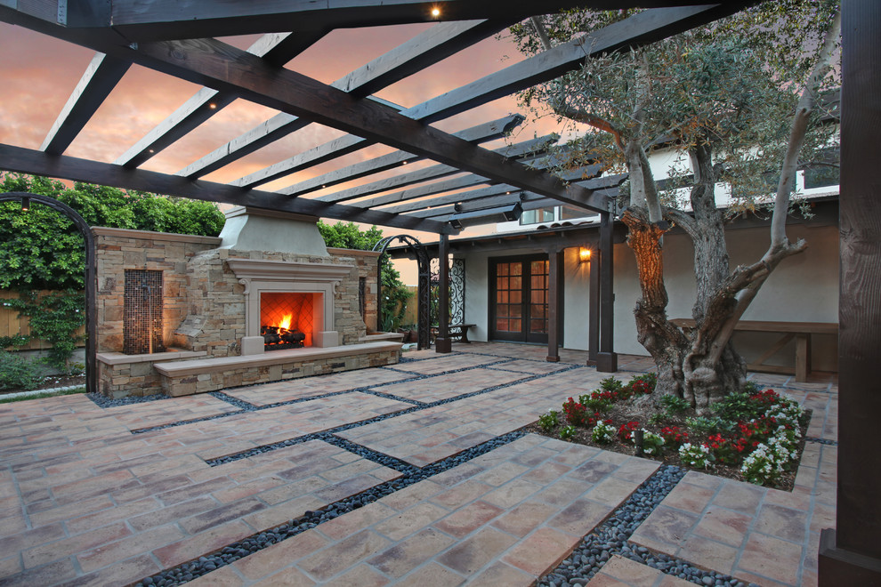 Design ideas for a mid-sized mediterranean courtyard patio in Orange County with a fire feature, natural stone pavers and a gazebo/cabana.
