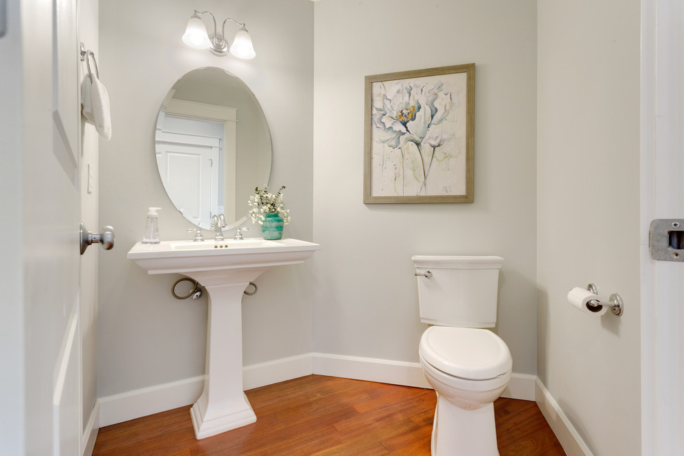 Mid-sized transitional powder room in Seattle with a one-piece toilet, grey walls, medium hardwood floors and a pedestal sink.