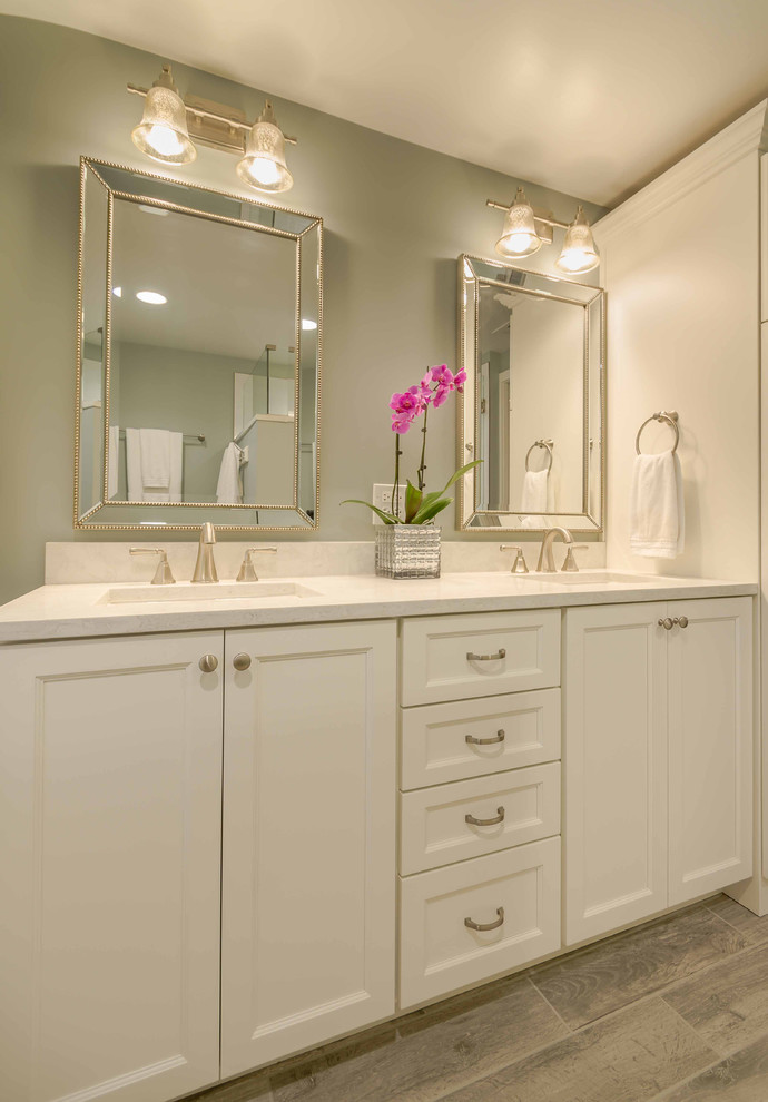 Photo of a mid-sized country master bathroom in Chicago with shaker cabinets, white cabinets, an alcove shower, a two-piece toilet, white tile, marble, grey walls, ceramic floors, an undermount sink, solid surface benchtops, grey floor, a hinged shower door, white benchtops, a double vanity, a freestanding vanity, wallpaper and decorative wall panelling.
