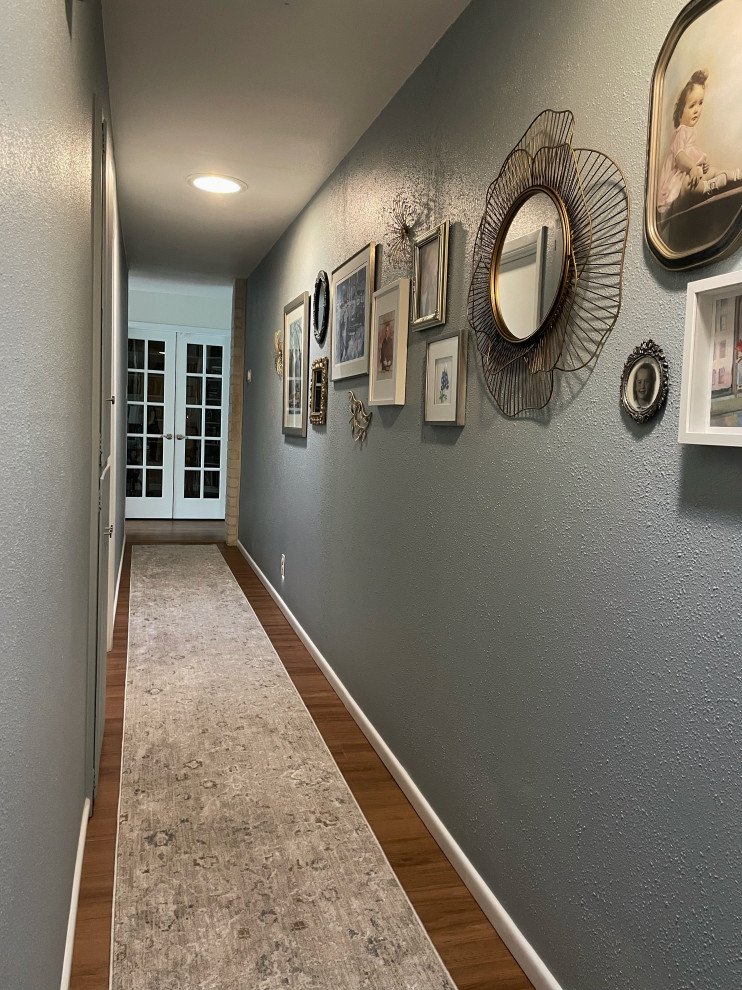 Example of a medium tone wood floor hallway design with blue walls
