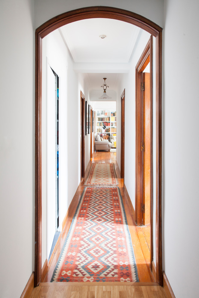 Photo of a mid-sized transitional hallway in Other with white walls, medium hardwood floors and brown floor.