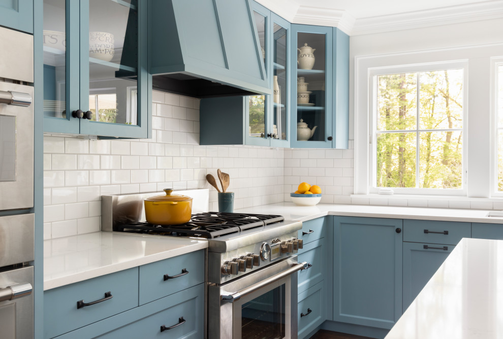 Bild på ett mycket stort vintage vit vitt kök, med en undermonterad diskho, luckor med profilerade fronter, blå skåp, bänkskiva i kvarts, vitt stänkskydd, stänkskydd i keramik, rostfria vitvaror, mellanmörkt trägolv och en köksö