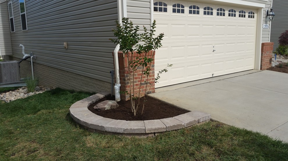 This is an example of a small contemporary front driveway full sun garden for summer in Baltimore with a retaining wall and gravel.