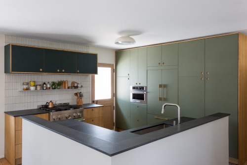 Kitchens and Bathrooms modern kitchen with matte olive-green flat-panel cabinets, oak accents, vertical tile backsplash, dark peninsula sink, and built-in wall oven.