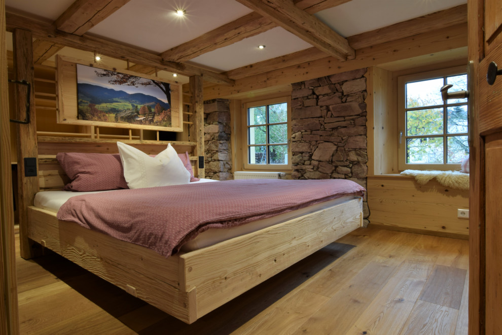 Aménagement d'une chambre parentale montagne de taille moyenne avec un mur blanc, parquet foncé, poutres apparentes et du lambris de bois.