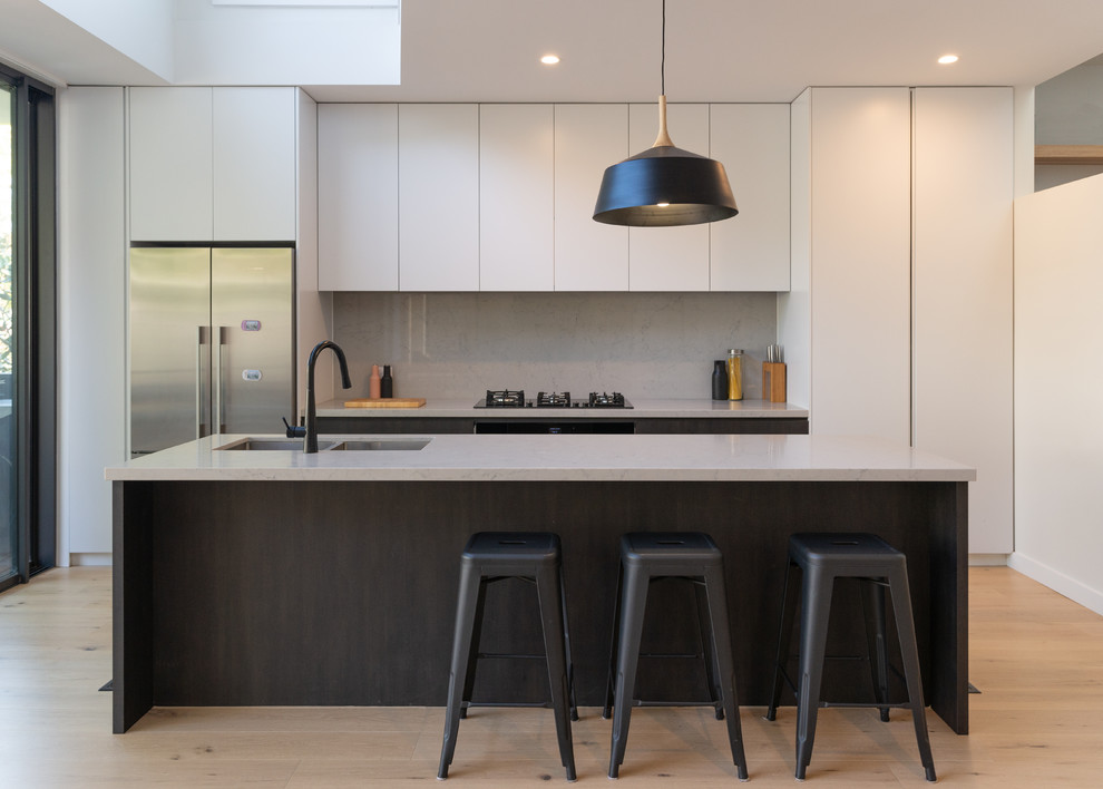Inspiration for a mid-sized contemporary galley open plan kitchen in Sydney with an undermount sink, flat-panel cabinets, dark wood cabinets, quartz benchtops, grey splashback, stone slab splashback, black appliances, light hardwood floors, with island and multi-coloured benchtop.