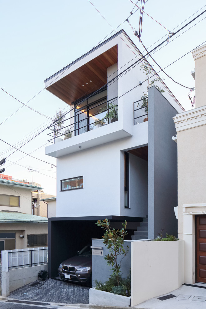 This is an example of a contemporary three-storey white house exterior in Tokyo with a flat roof.