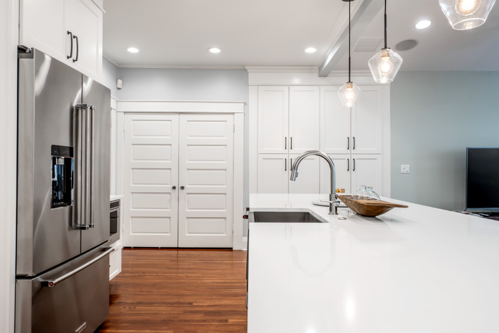Large traditional u-shaped separate kitchen in Tampa with a farmhouse sink, recessed-panel cabinets, white cabinets, quartz benchtops, green splashback, glass tile splashback, stainless steel appliances, medium hardwood floors, with island, brown floor and white benchtop.