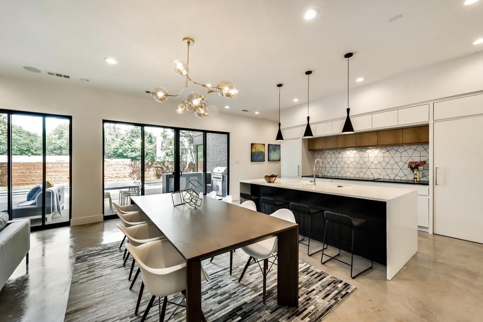 This is an example of a midcentury open plan kitchen in Dallas with flat-panel cabinets, multi-coloured splashback, concrete floors, with island and grey floor.