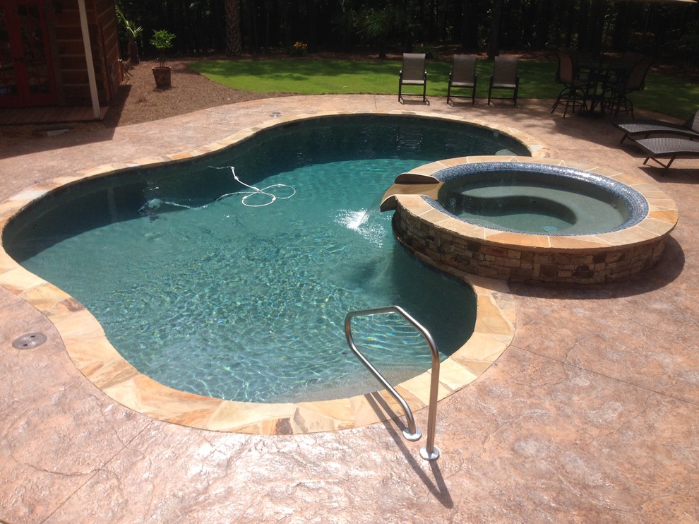 This is an example of a small traditional backyard custom-shaped pool in Atlanta with a hot tub and stamped concrete.