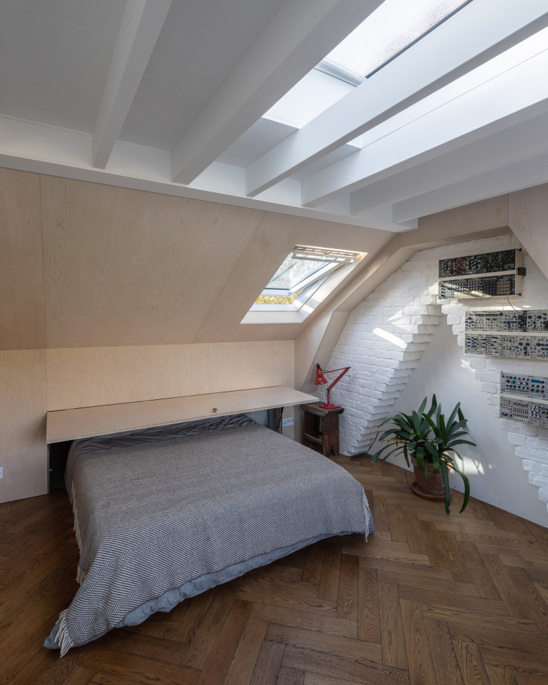 Medium sized bohemian guest bedroom in London with medium hardwood flooring, exposed beams, wood walls and a chimney breast.