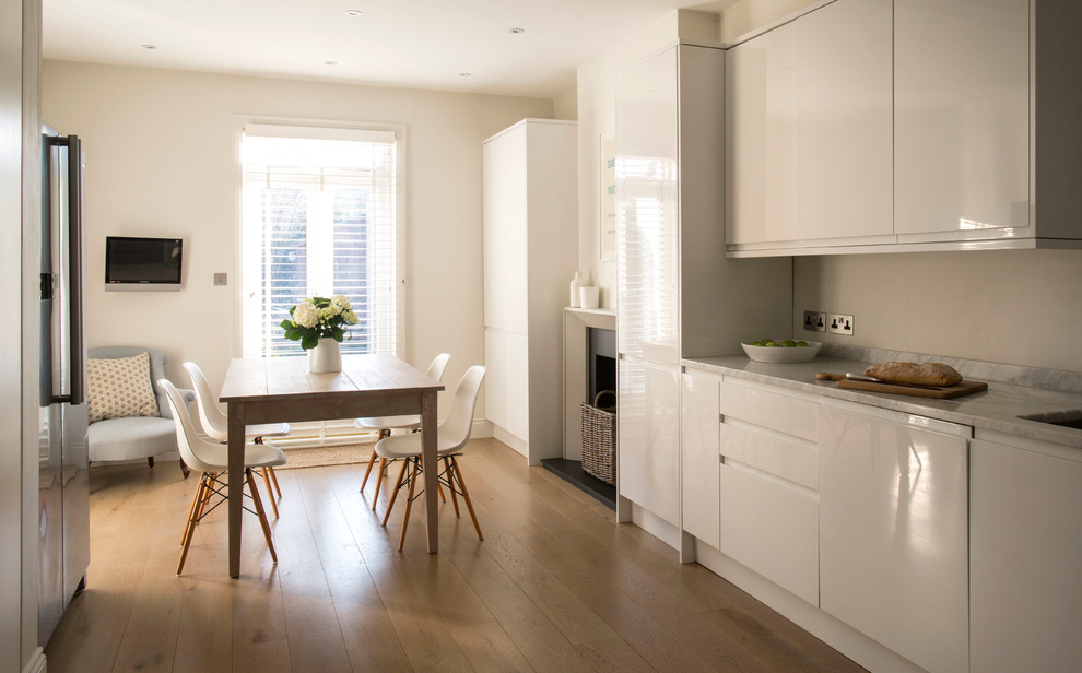 Contemporary kitchen in Other with flat-panel cabinets, white cabinets, beige splashback and light hardwood floors.