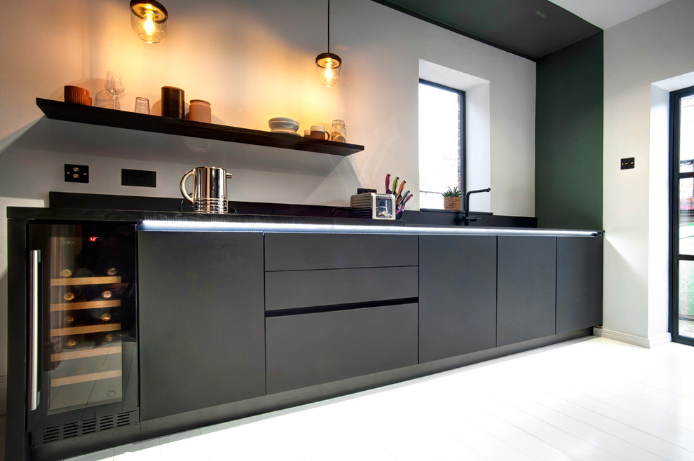 Design ideas for a small modern galley separate kitchen in Other with a single-bowl sink, flat-panel cabinets, black cabinets, quartzite benchtops, black splashback, glass sheet splashback, black appliances, painted wood floors, no island, white floor and black benchtop.