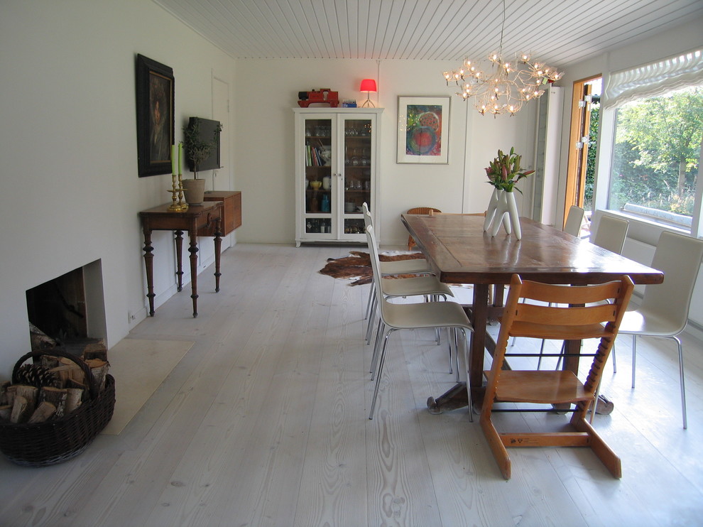 Scandinavian dining room in Other with white walls, painted wood flooring and a standard fireplace.