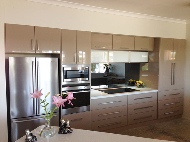 This is an example of a contemporary single-wall eat-in kitchen in Perth with an undermount sink, raised-panel cabinets, beige cabinets, quartz benchtops, black splashback, glass sheet splashback, stainless steel appliances, cement tiles and no island.