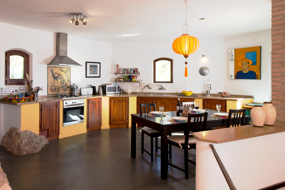 This is an example of a large classic single-wall kitchen/diner with shaker cabinets, dark wood cabinets, white splashback, stainless steel appliances, no island and slate flooring.
