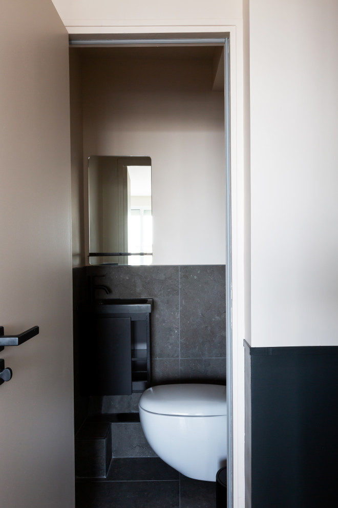 Idéer för små funkis svart toaletter, med luckor med profilerade fronter, svarta skåp, en vägghängd toalettstol, grå kakel, keramikplattor, beige väggar, klinkergolv i keramik, ett väggmonterat handfat, bänkskiva i kvarts och grått golv