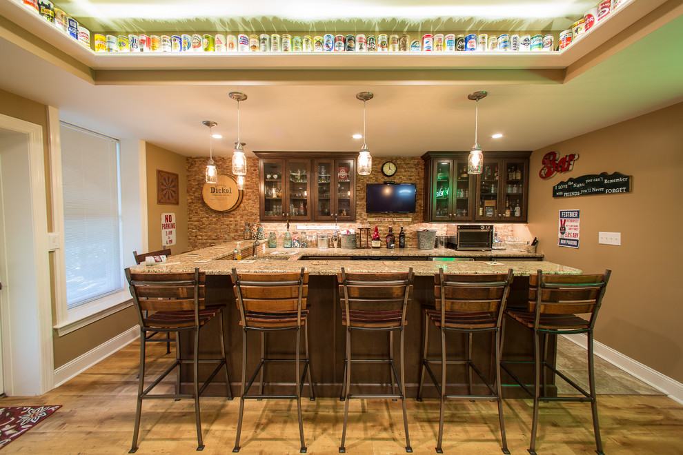 Large country u-shaped seated home bar in Philadelphia with an undermount sink, shaker cabinets, dark wood cabinets, granite benchtops, brown splashback, matchstick tile splashback, ceramic floors and brown floor.