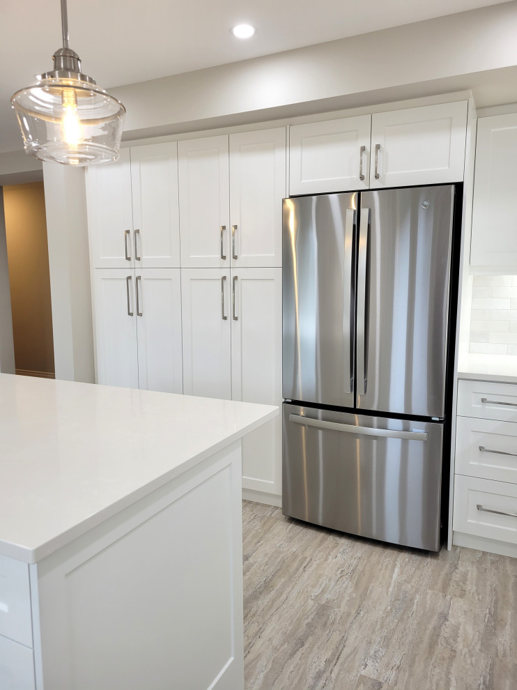 Example of a huge transitional u-shaped vinyl floor and multicolored floor eat-in kitchen design with an undermount sink, white cabinets, quartzite countertops, gray backsplash, stone tile backsplash, stainless steel appliances, an island and white countertops