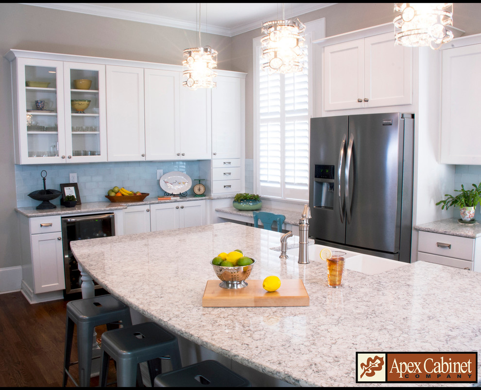 This is an example of a large transitional u-shaped eat-in kitchen in Raleigh with a farmhouse sink, recessed-panel cabinets, white cabinets, granite benchtops, glass tile splashback, stainless steel appliances, medium hardwood floors and with island.