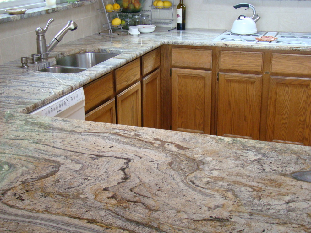 Example of a mid-sized arts and crafts l-shaped light wood floor kitchen design in Seattle with a double-bowl sink, recessed-panel cabinets, medium tone wood cabinets, granite countertops, white backsplash, porcelain backsplash and stainless steel appliances