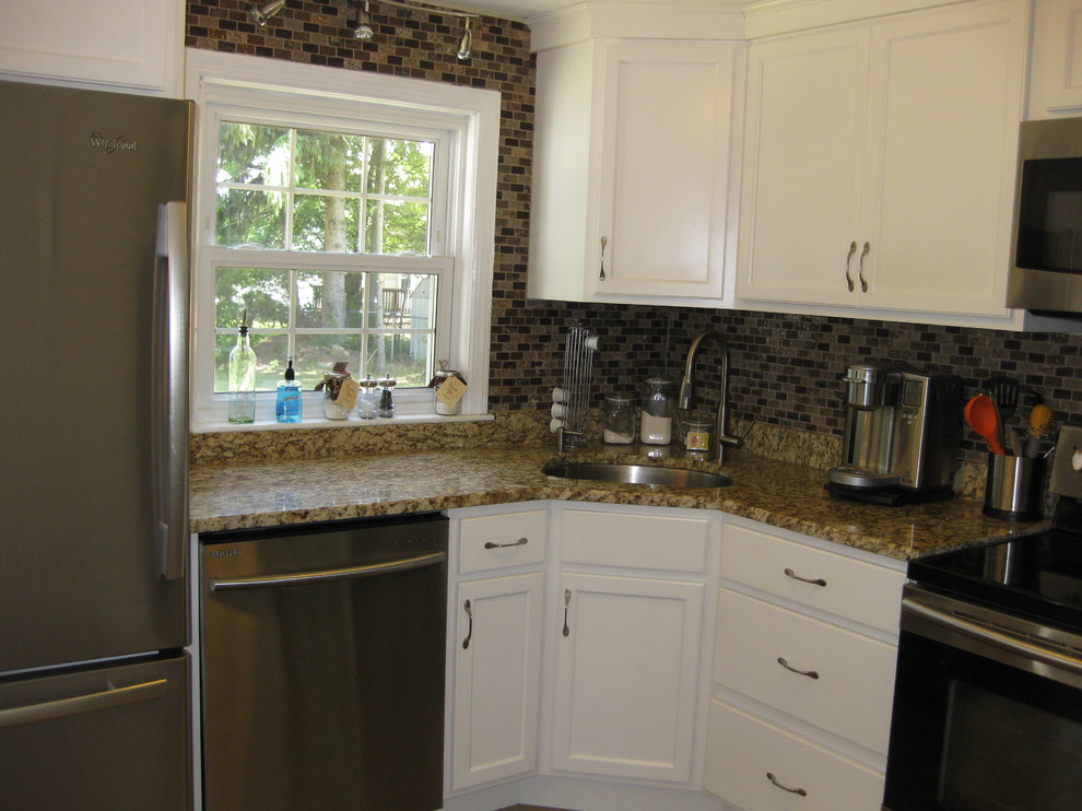 Small transitional l-shaped porcelain tile and brown floor kitchen photo in Boston with an undermount sink, recessed-panel cabinets, white cabinets, granite countertops, brown backsplash, stainless steel appliances, no island, glass tile backsplash and beige countertops