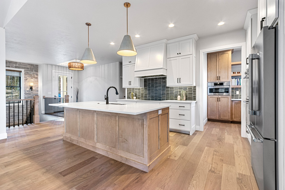 Inspiration for a large transitional l-shaped medium tone wood floor and brown floor eat-in kitchen remodel with an undermount sink, shaker cabinets, white cabinets, quartz countertops, green backsplash, porcelain backsplash, stainless steel appliances, an island and white countertops