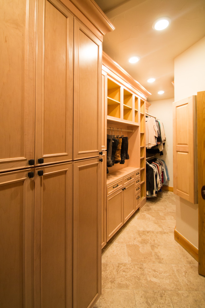This is an example of a large traditional gender-neutral walk-in wardrobe in Denver with raised-panel cabinets, light wood cabinets, travertine floors and beige floor.